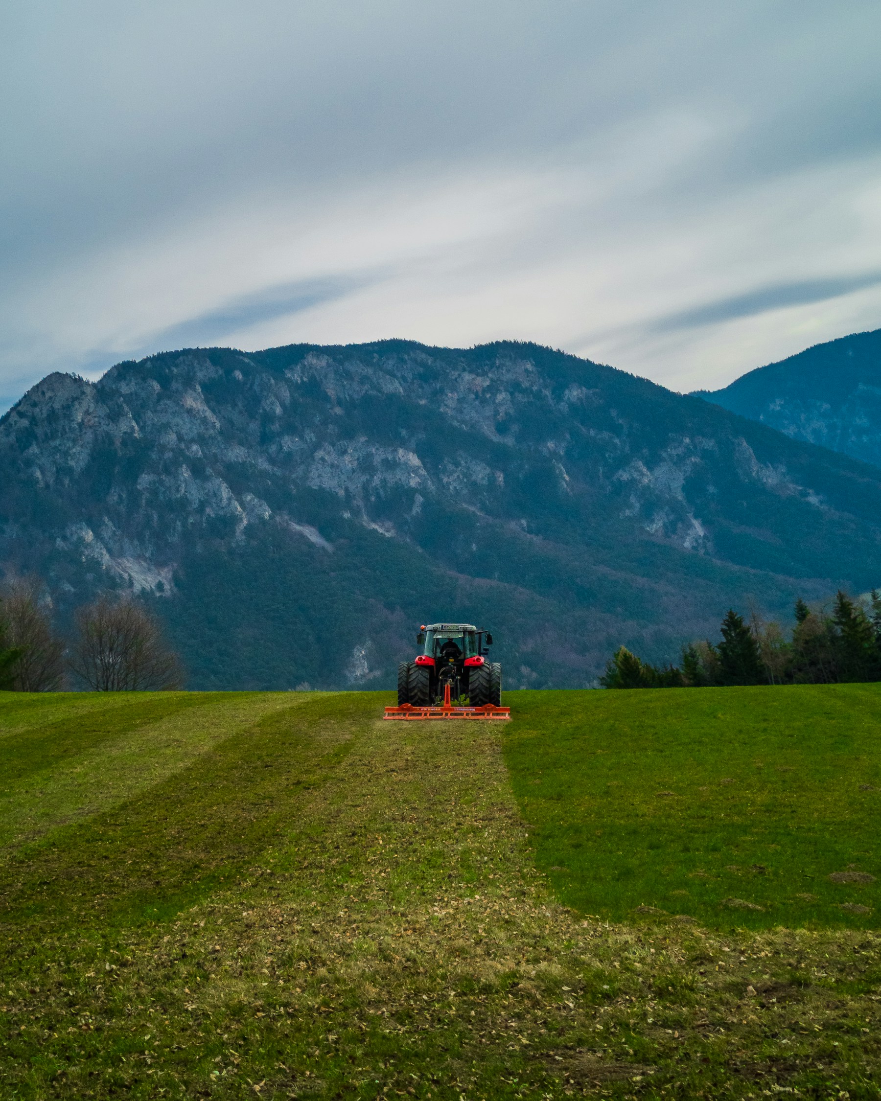 Traktor auf einer landwirtschaftlichen Fläche vor österreichischer Berglandschaft